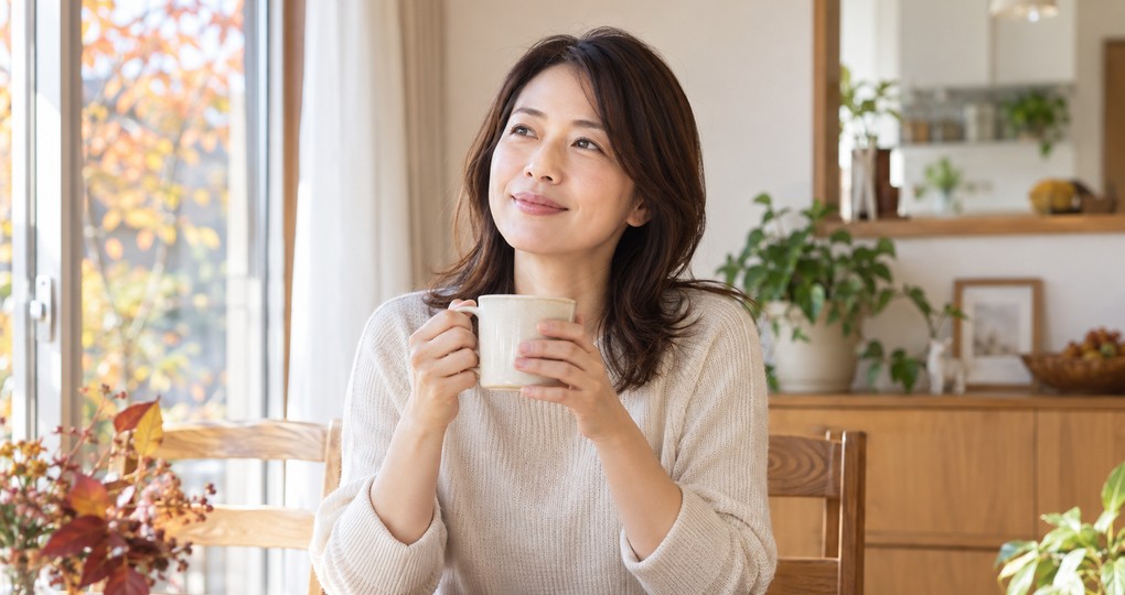 秋の朝に温かいコーヒーを飲む女性