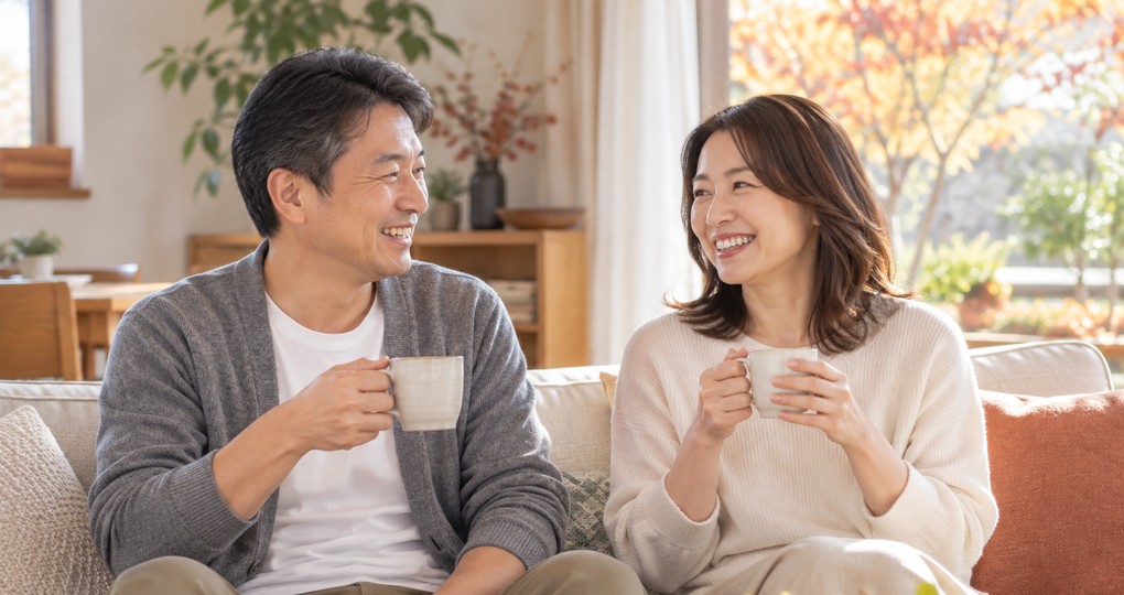 秋のリビングで温かい飲み物を手に笑い合う夫婦